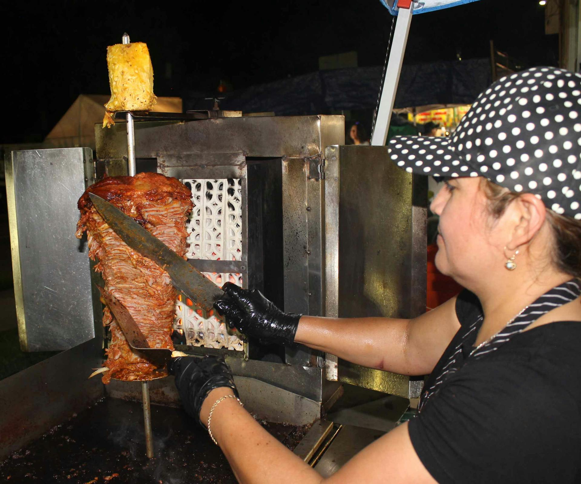 conchis cutting meat off of the trompo while spinning it