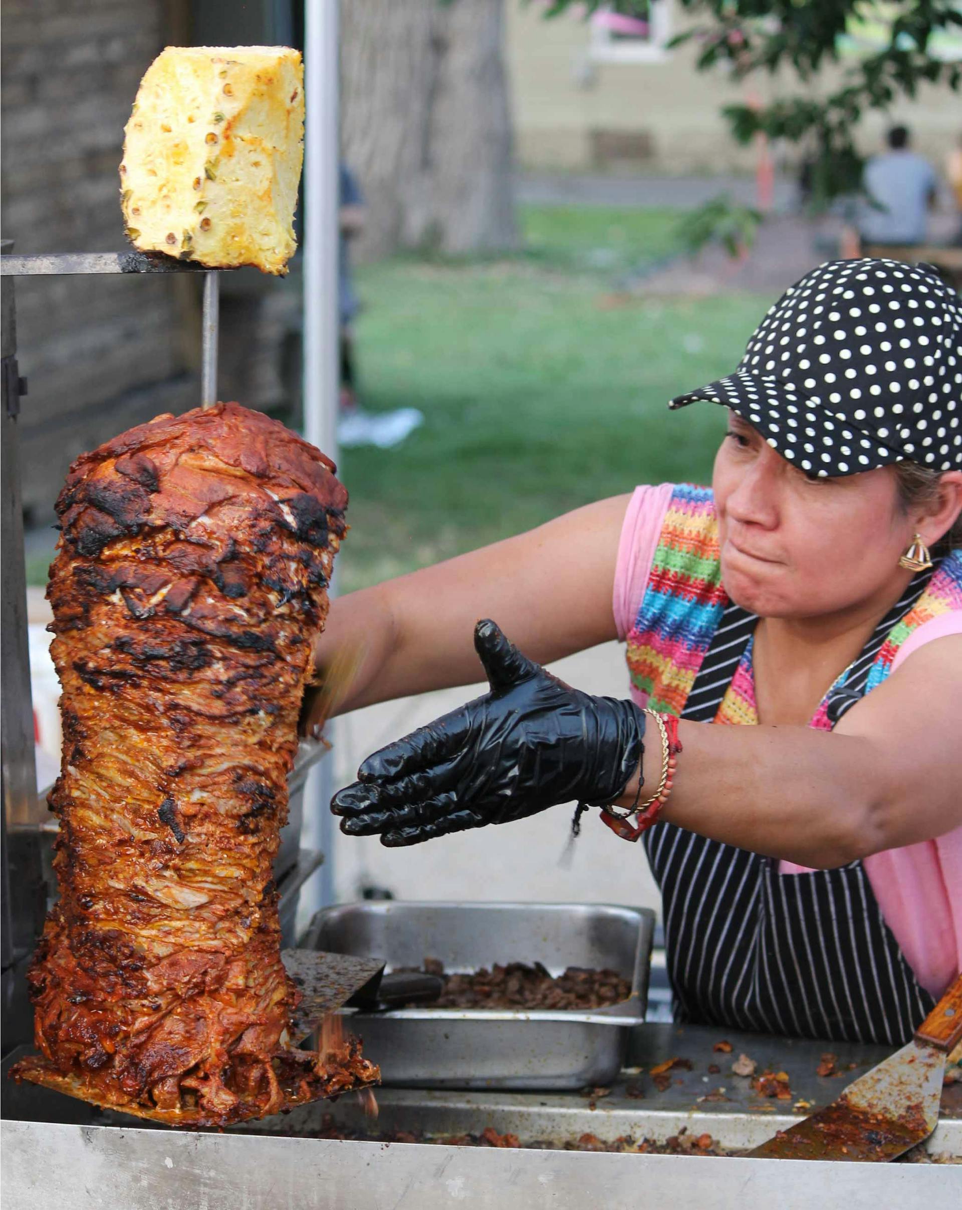 conchis spinning the trompo and cutting some of the pork off while spinning it