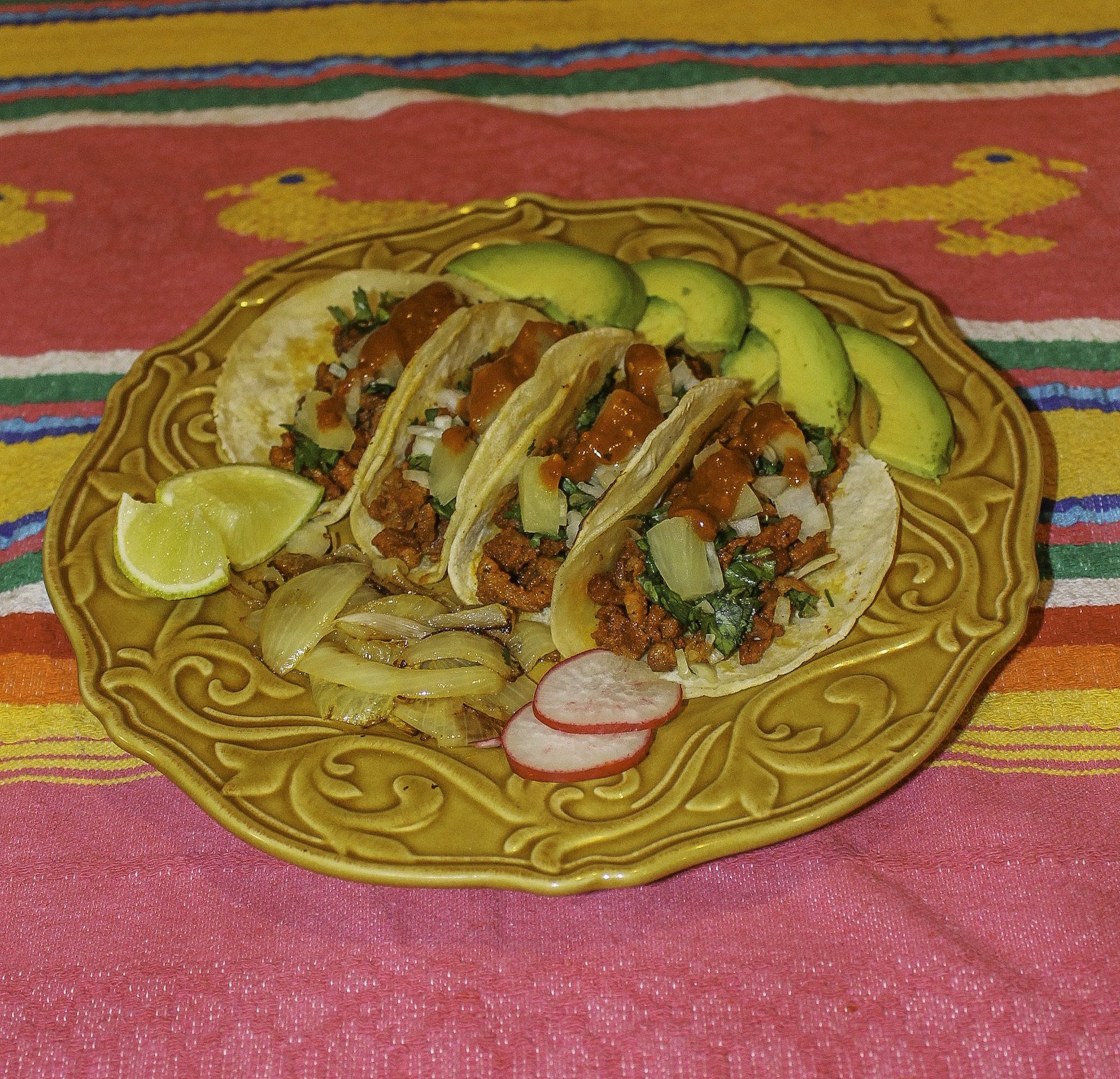 4 pork pastor tacos with limes, grilled onions, and radishes