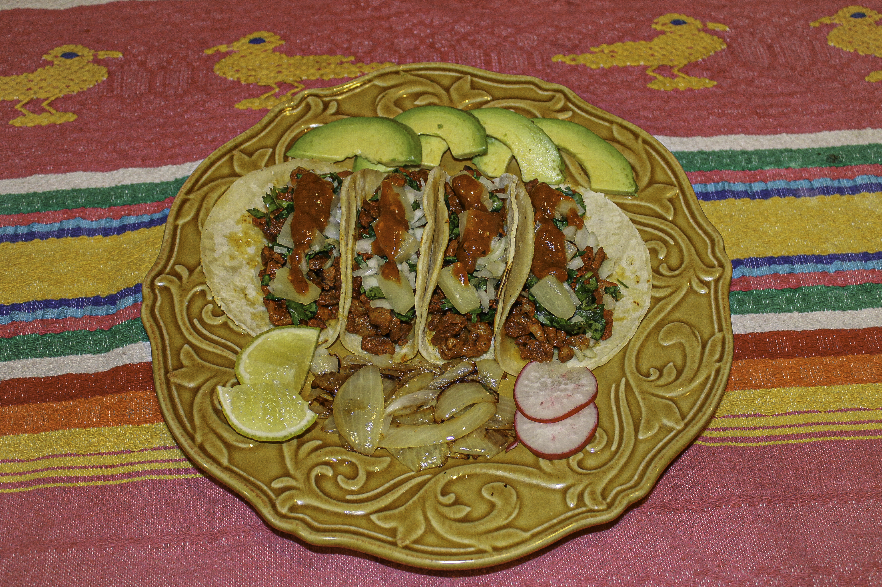 4 pork pastor tacos with limes, grilled onions, and radishes